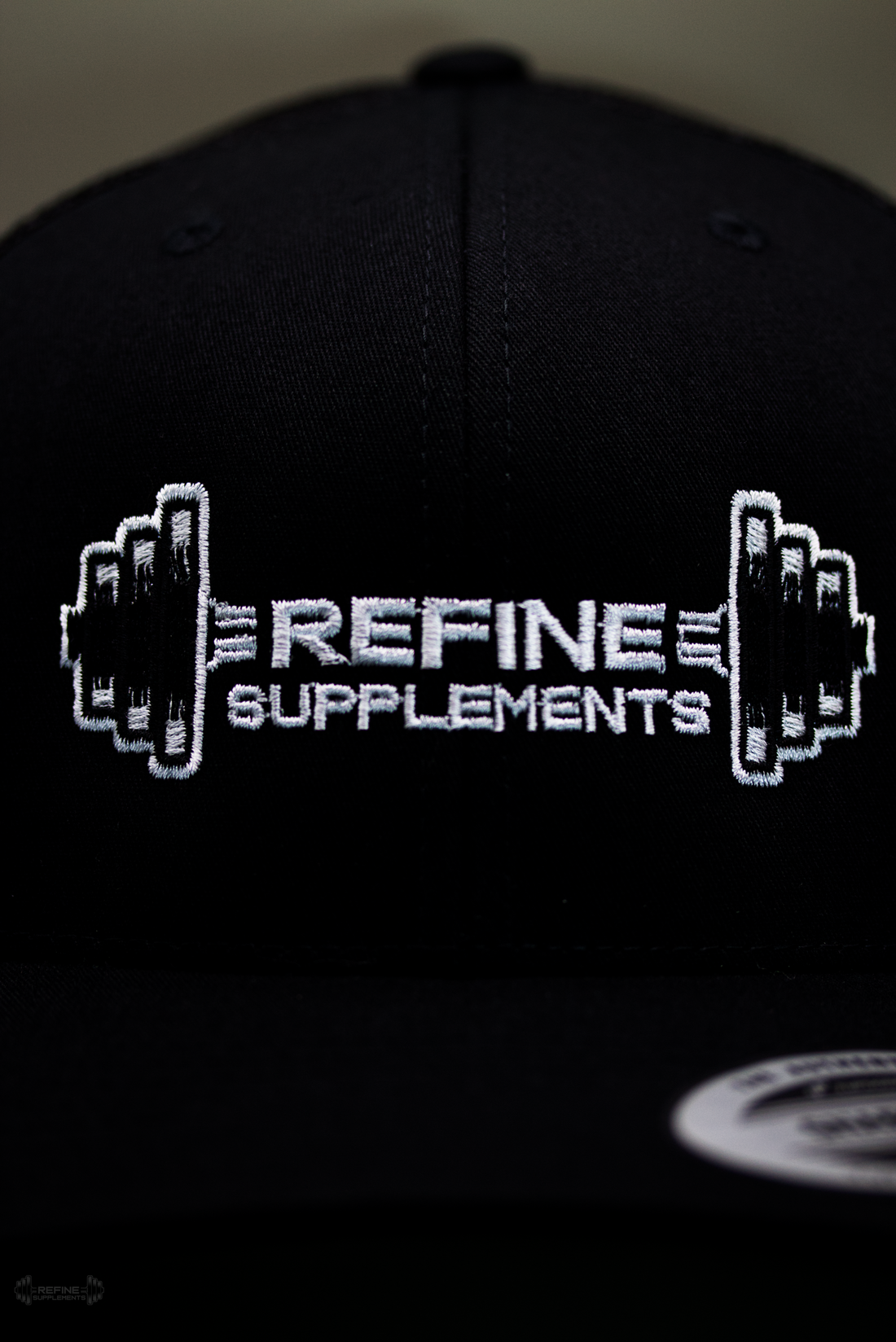 Black cap with 'Refine Supplements' logo on a dark background